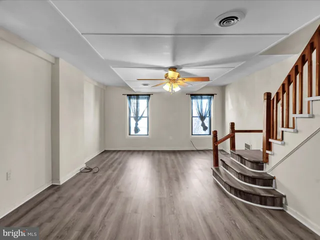 a view of a hallway with wooden floor and a kitchen