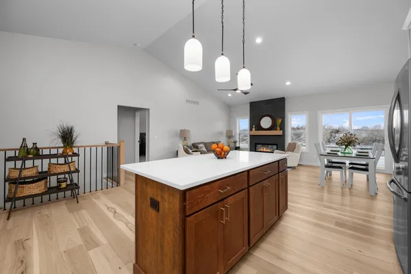 a large white kitchen with a large island oven a stove dining table and chairs