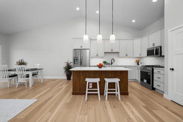 a kitchen with stainless steel appliances a dining table chairs stove and white cabinets