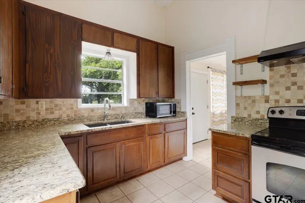 a kitchen with stainless steel appliances granite countertop wooden cabinets sink and stove top oven