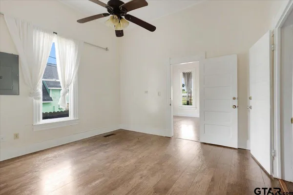 a view of an empty room with wooden floor and a window