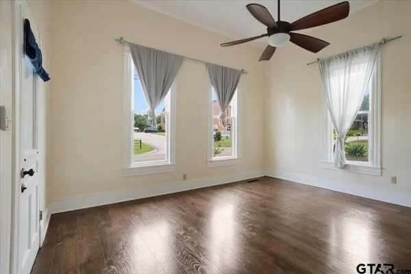 an empty room with wooden floor fan and windows