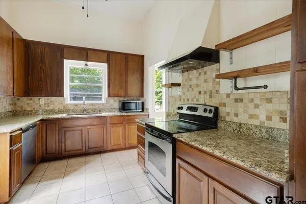 a kitchen with stainless steel appliances granite countertop a stove a sink and a microwave
