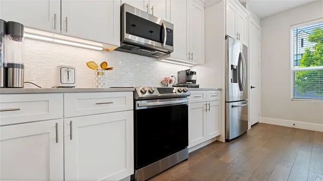 a kitchen with stainless steel appliances granite countertop a refrigerator stove a sink and dishwasher with wooden floor