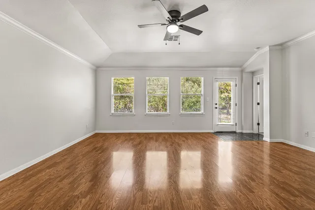 a view of an empty room with wooden floor and a window