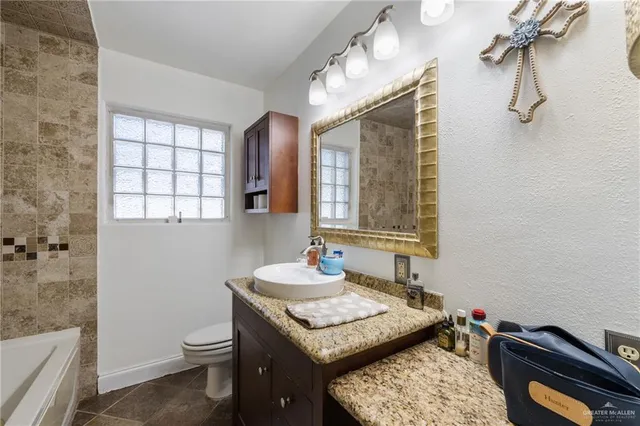 a bathroom with a granite countertop sink a toilet and shower