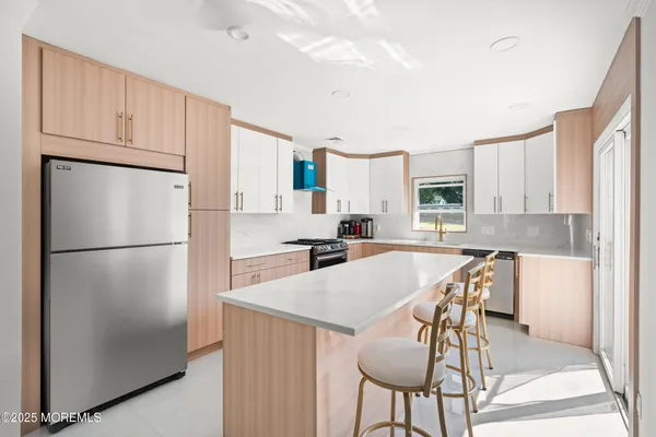 a kitchen with stainless steel appliances a refrigerator a stove a dining table and chairs