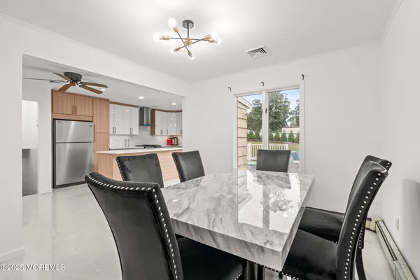 a living room with stainless steel appliances furniture a dining table and a chandelier