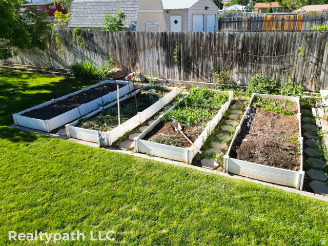 475 South 300 East Payson, UT 84651 - Photo 10 of 12 Expansive backyard featuring a manicured lawn, a wooden privacy fence, and four raised garden beds with stepping stones