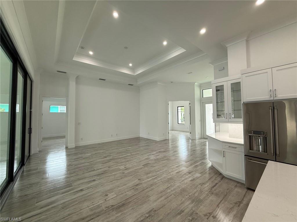 82 Tahiti Road Marco Island, FL 34145 - Photo 11 of 27 a view of an empty room with wooden floor and a kitchen