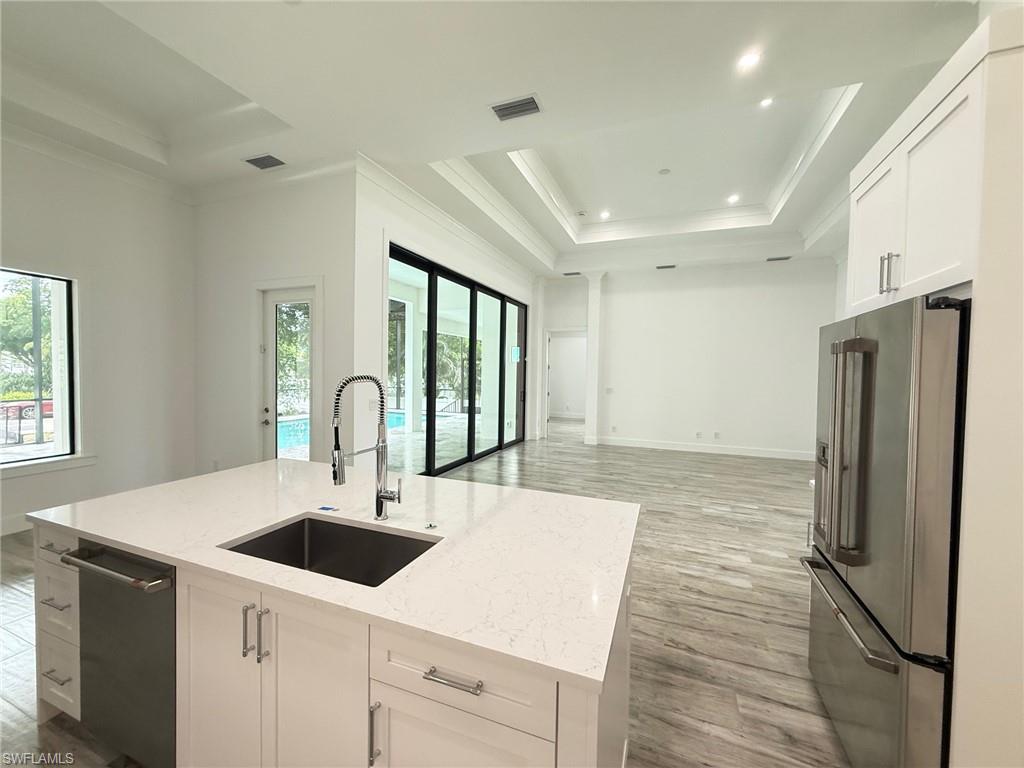 82 Tahiti Road Marco Island, FL 34145 - Photo 15 of 27 a kitchen with stainless steel appliances a sink a stove a refrigerator with white cabinets and wooden floor