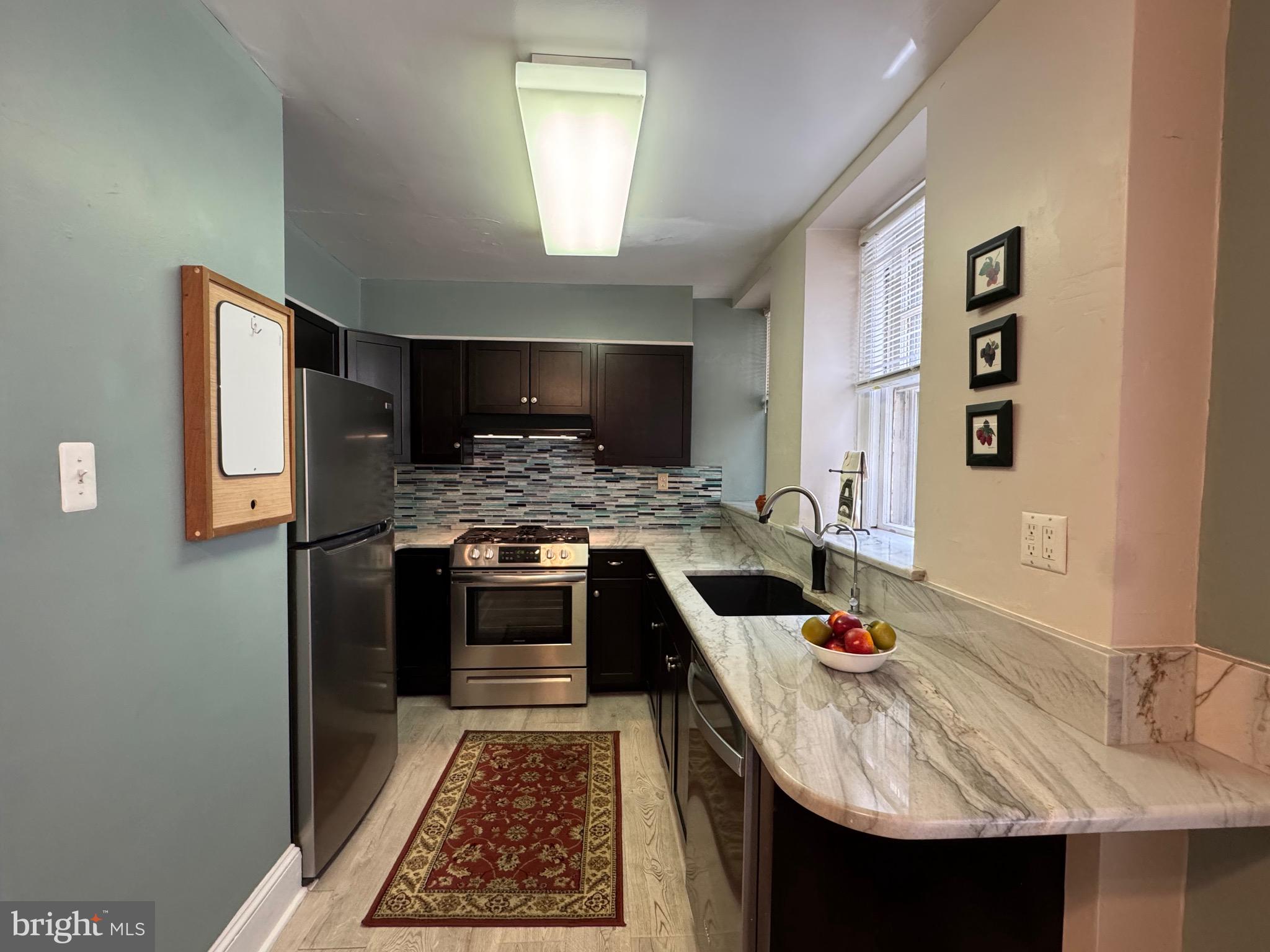 4643 Pine Street, Unit C411 Philadelphia, PA 19143 - Photo 29 of 63 a kitchen with stainless steel appliances granite countertop a sink stove and refrigerator