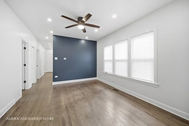 a view of empty room with wooden floor and fan