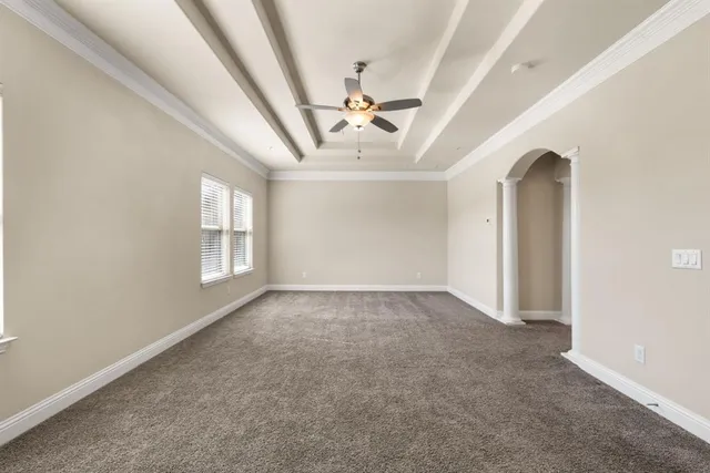 an empty room with windows and ceiling fan