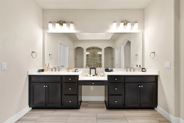 a spacious bathroom with a granite countertop double vanity and mirrors