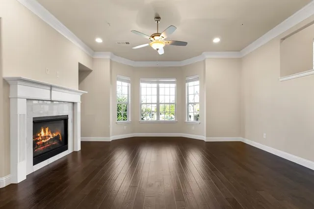 a view of an empty room with wooden floor fireplace and a window