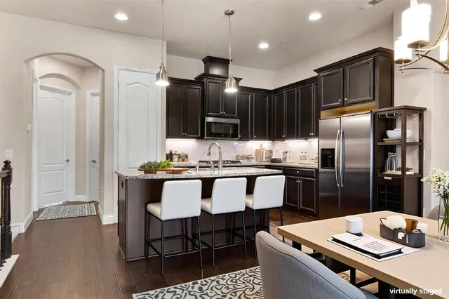 a kitchen with kitchen island granite countertop a sink stove and refrigerator with wooden floor