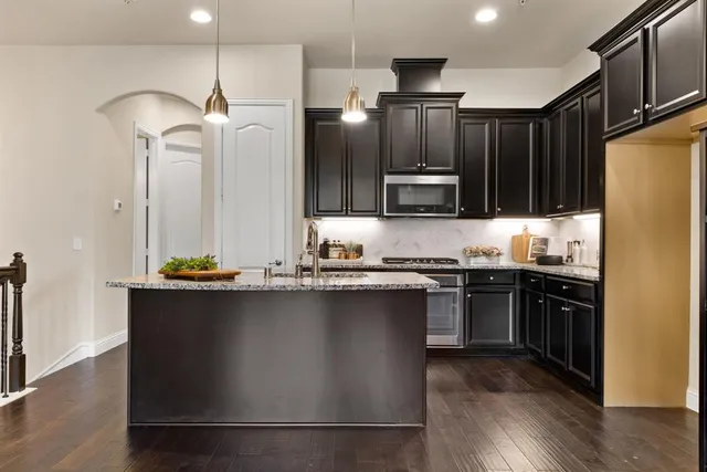 a kitchen with stainless steel appliances granite countertop a sink a stove and refrigerator