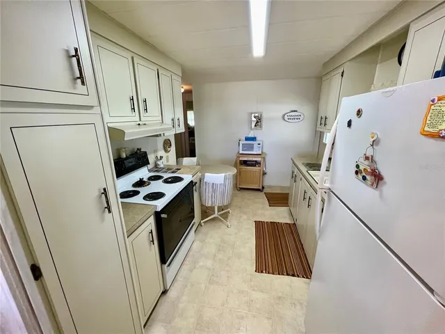 a kitchen with stainless steel appliances a stove a refrigerator a sink a stove and white cabinets