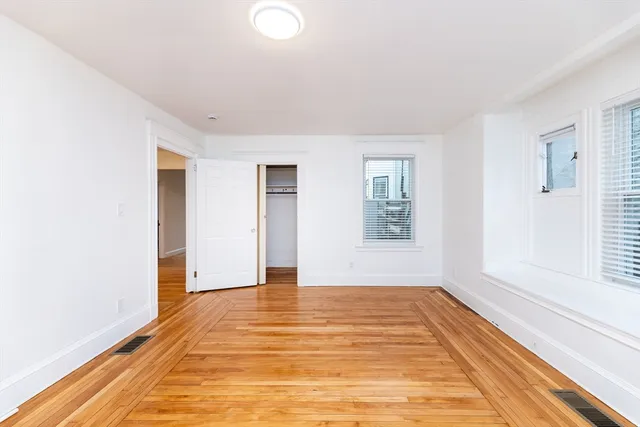 a view of an empty room with window and wooden floor