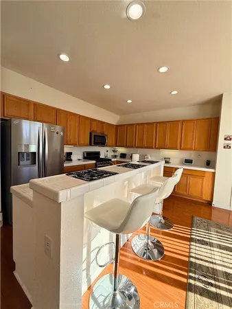 a kitchen with stainless steel appliances granite countertop a refrigerator a stove and a sink with wooden floor