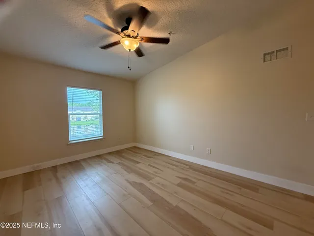 an empty room with wooden floor and windows