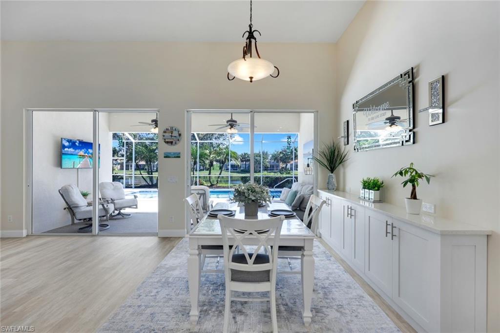 3108 Dominica Way Naples, FL 34119 - Photo 7 of 39 Dining area featuring high ceilings, wood-finish flooring, and expansive sliding glass doors opening to a screened lanai overlooking your private pool.