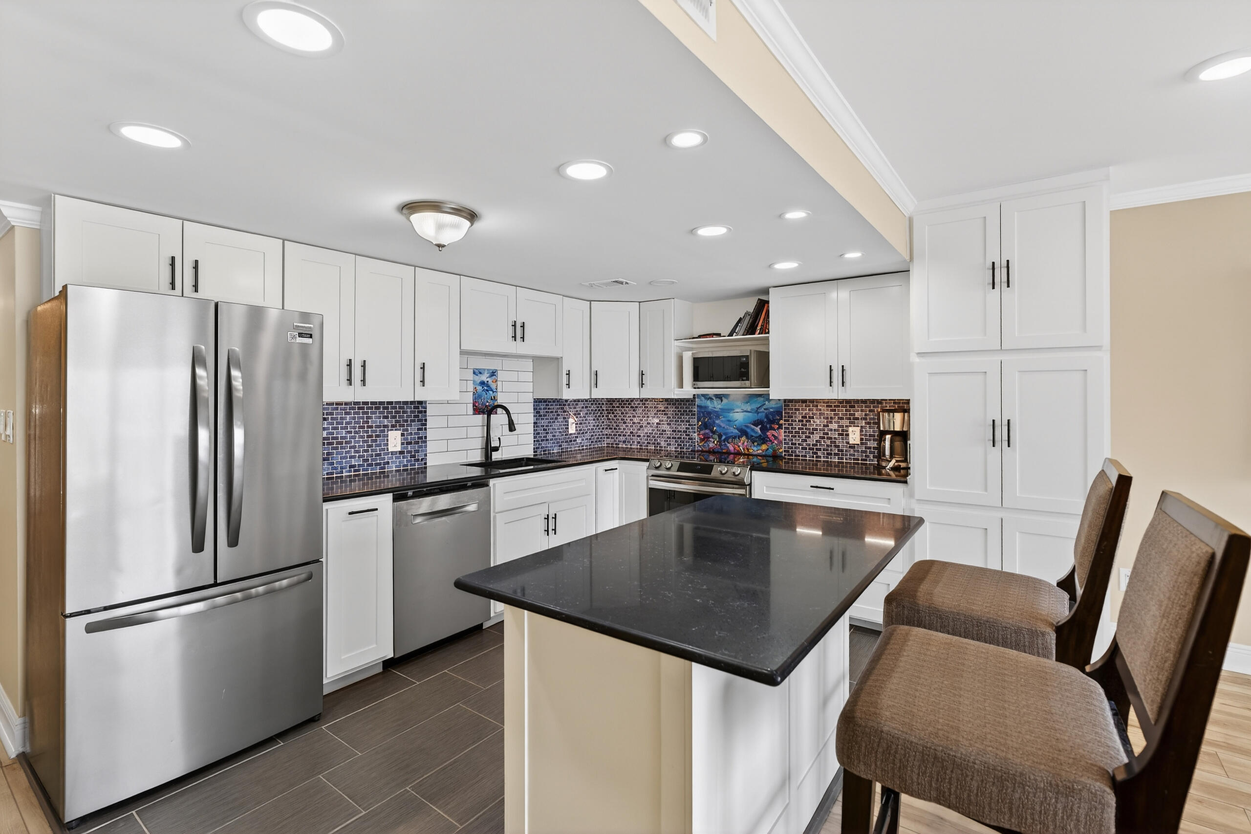 151 Calhoun Avenue, Unit 301 Destin, FL 32541 - Photo 11 of 43 a kitchen with stainless steel appliances granite countertop a refrigerator a stove a sink a dining table and chairs