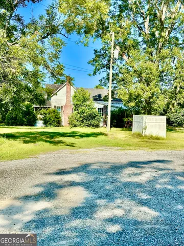 a view of a house with a big yard and large trees