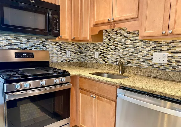 a kitchen with granite countertop stainless steel appliances a sink stove and microwave