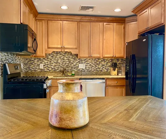 a kitchen with stainless steel appliances kitchen island granite countertop a refrigerator a stove a sink and dishwasher with wooden floor