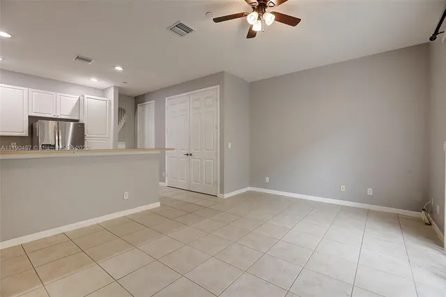 an empty room with chandelier fan and windows
