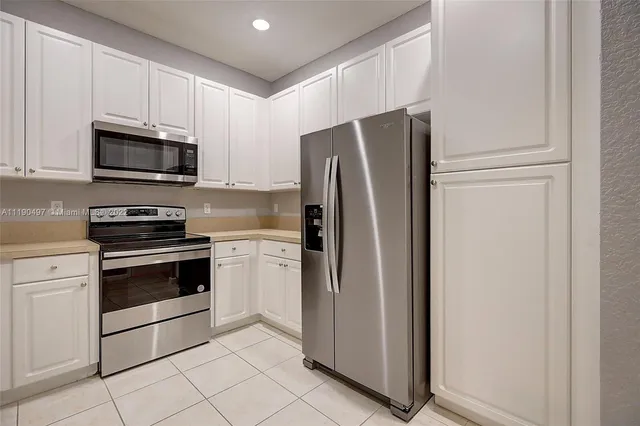 a kitchen with stainless steel appliances white cabinets and a refrigerator