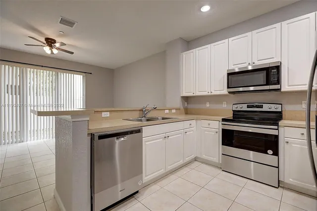 a kitchen with granite countertop a sink stainless steel appliances and cabinets