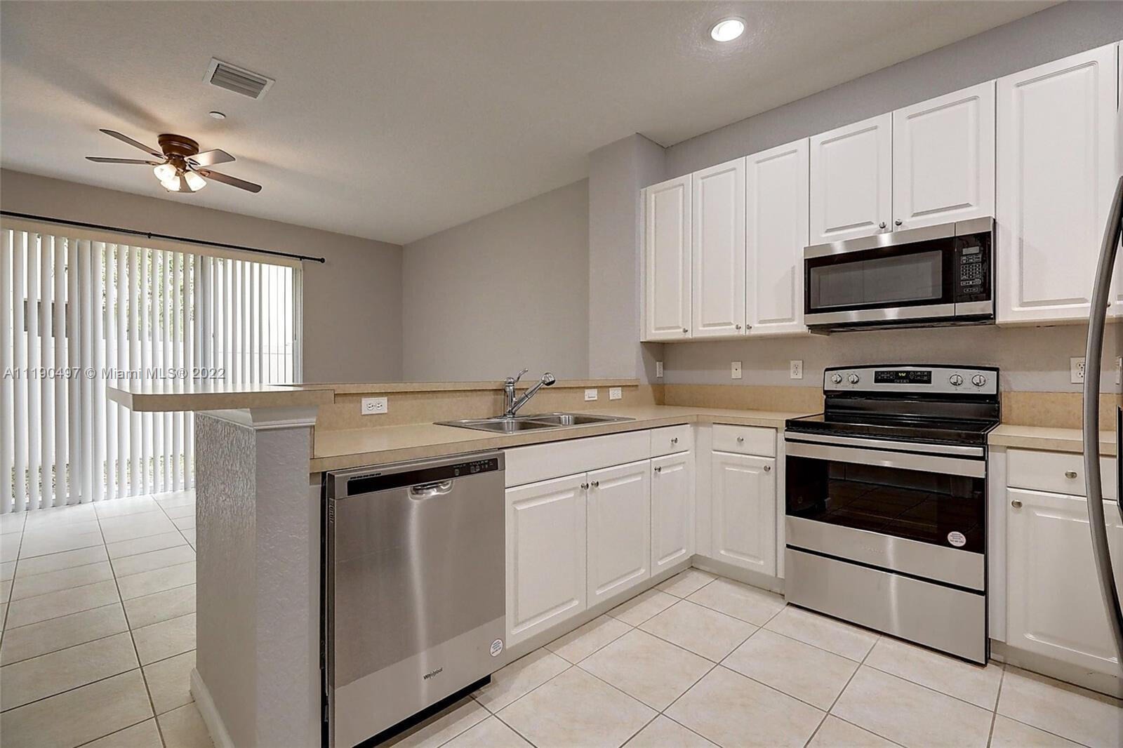 9469 Southwest Purple Martin Way Stuart, FL 34997 - Photo 6 of 21 a kitchen with granite countertop a sink stainless steel appliances and cabinets