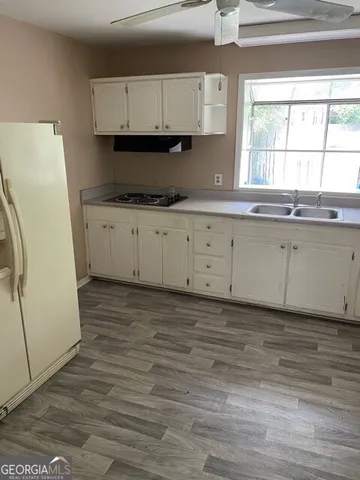 a kitchen with granite countertop a refrigerator sink and cabinets