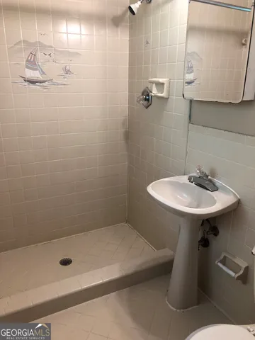 a bathroom with a shower a sink and mirror