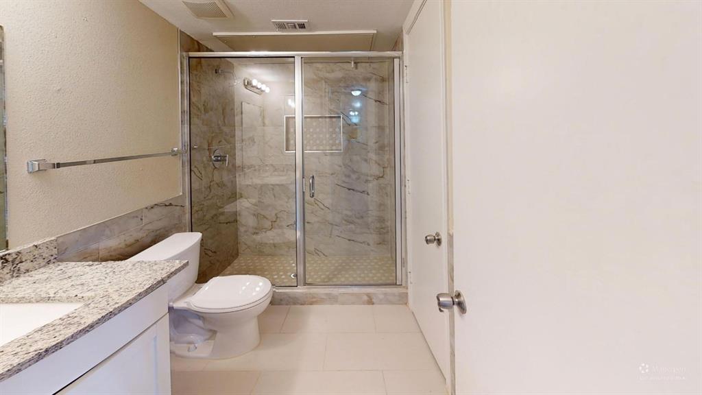 9837 Walnut Street, Unit 103 Dallas, TX 75243 - Photo 10 of 10 Bathroom with vanity, a marble finish shower, light tile patterned floors, and a textured wall
