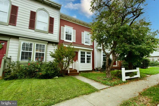 a white house that has a big yard and couches chairs with wooden fence