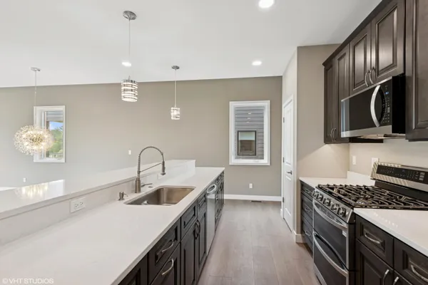 a kitchen with kitchen island granite countertop a sink stove and cabinets