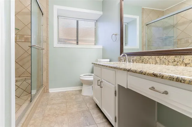 a bathroom with a granite countertop sink a toilet and a mirror