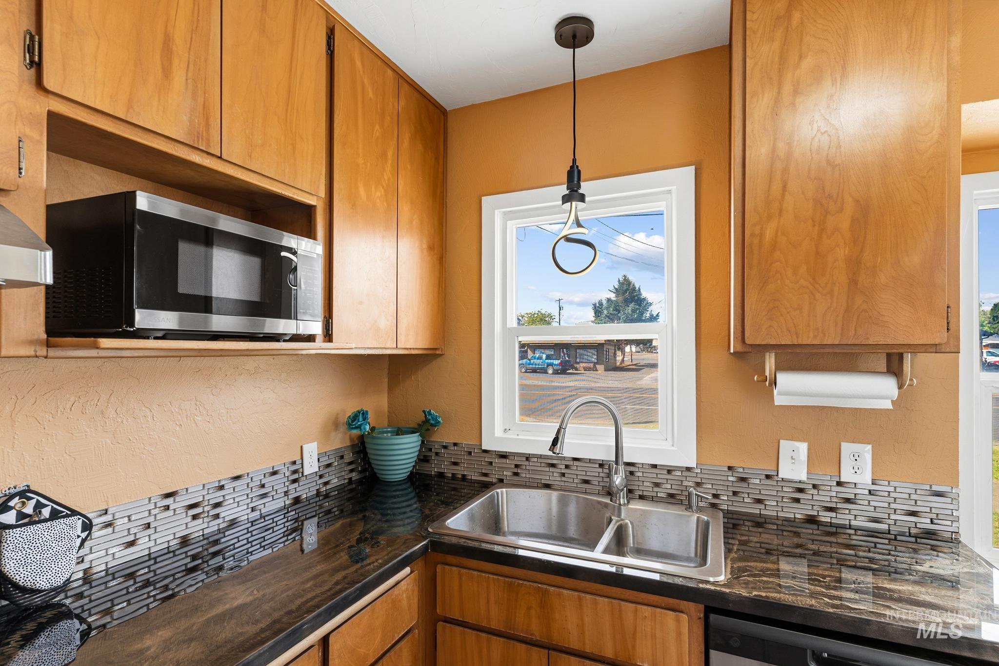 619 Thain Road Lewiston, ID 83501 - Photo 31 of 44 Kitchen featuring a double-basin stainless steel sink, dark granite countertops, and a mosaic tile backsplash