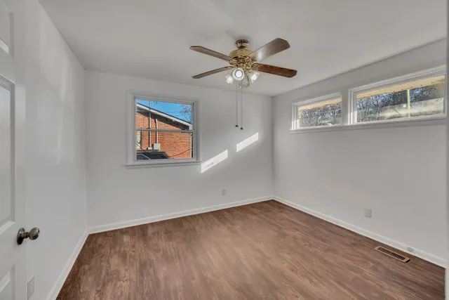 a view of empty room with wooden floor and fan