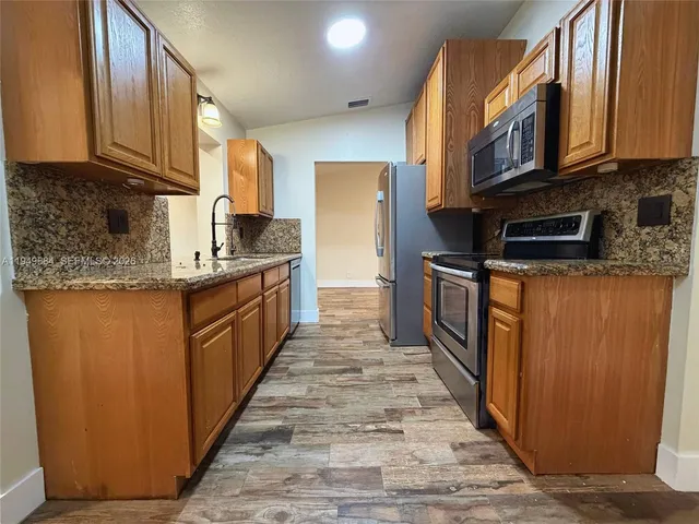 a kitchen with stainless steel appliances granite countertop a stove a sink dishwasher and a refrigerator