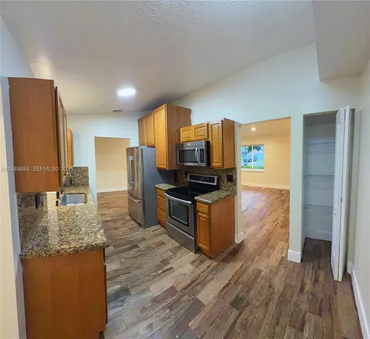 a kitchen with stainless steel appliances granite countertop a stove a sink and a refrigerator