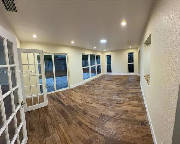 a view of an empty room with wooden floor and stairs