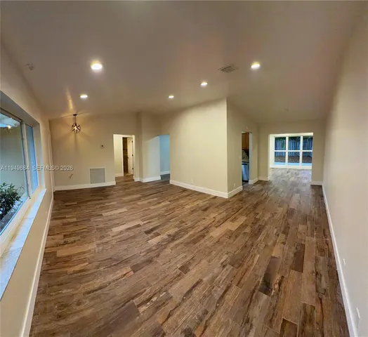 a view of a big room with wooden floor and windows