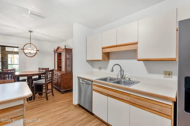 a kitchen with stainless steel appliances granite countertop a sink dishwasher a dining table and chairs with wooden floor