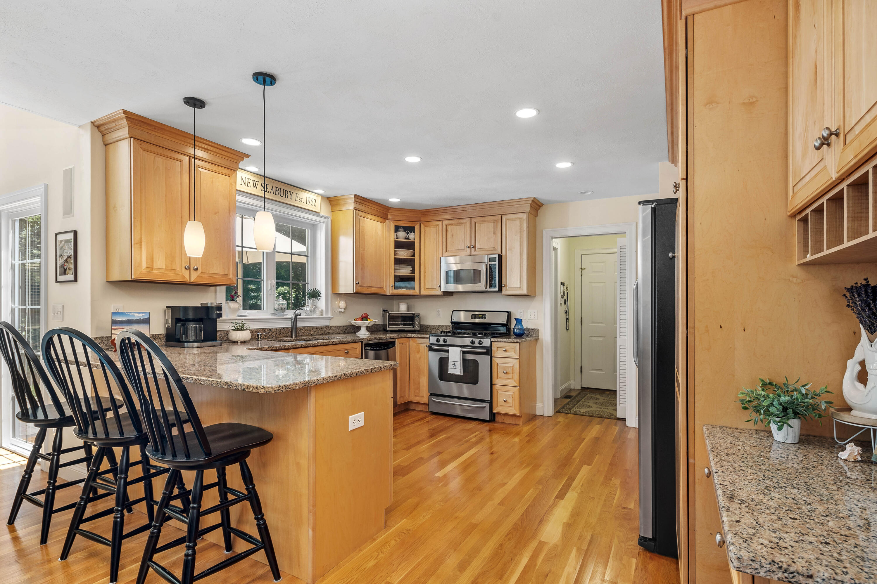 193 Fells Pond Road Mashpee, MA 02649 - Photo 12 of 33 a kitchen with stainless steel appliances kitchen island granite countertop a refrigerator a stove a sink and a dining table with wooden floor
