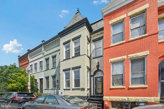 a front view of a building with lot of cars and trees